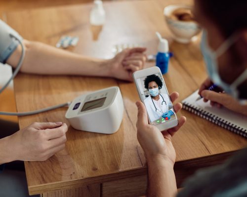 Close-up of black female doctor advising her patients who are measuring blood pressure at home during coronavirus pandemic.